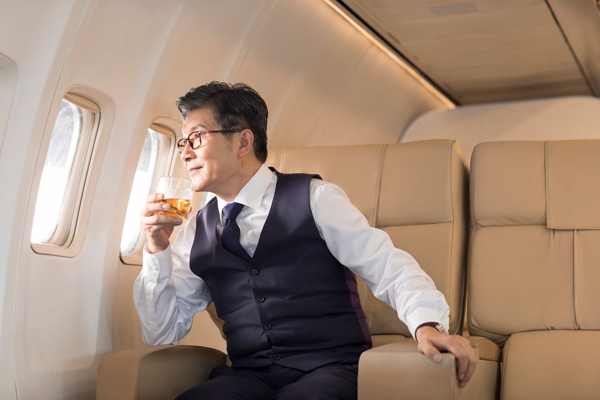 Senior businessman drinking whiskey on airplane