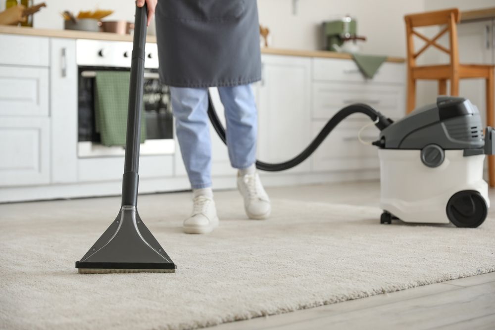 Young,Woman,Hoovering,Carpet,In,Kitchen,,Closeup