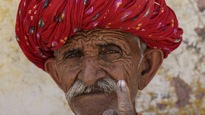 Egy férfi tintás ujját mutatja, miután leadta szavazatát egy szavazóhelyiségben az indiai általános választások második szakaszában