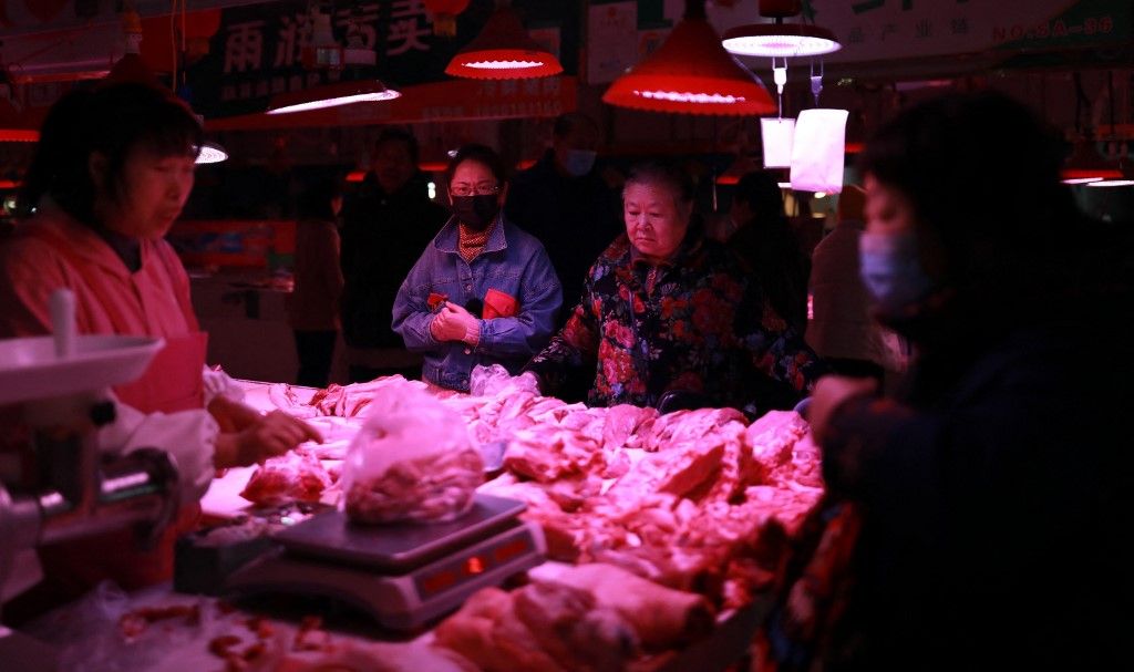 People shop for pork at a vendor's in a market in Shenyang city, northeast China's Liaoning province, 15 October 2020. (Photo by Tian Weitao / Imaginechina via AFP)