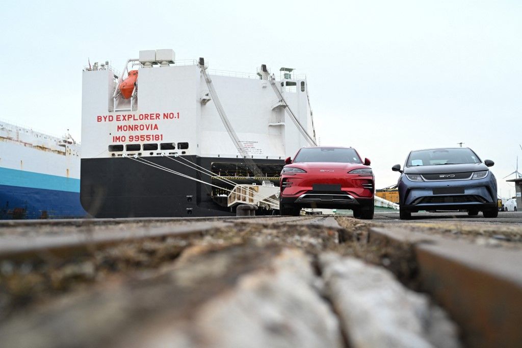 26 February 2024, Bremen, Bremerhaven: Two new cars, left of the model "Seal" (l) of the model "Dolphi" of the Chinese car manufacturer BYD stand in front of the car freighter BYD Explorer No.1". The BYD Explorer No.1 has arrived in Europe from Shenzen, China. Photo: Lars Penning/dpa (Photo by Lars Penning / DPA / dpa Picture-Alliance via AFP)