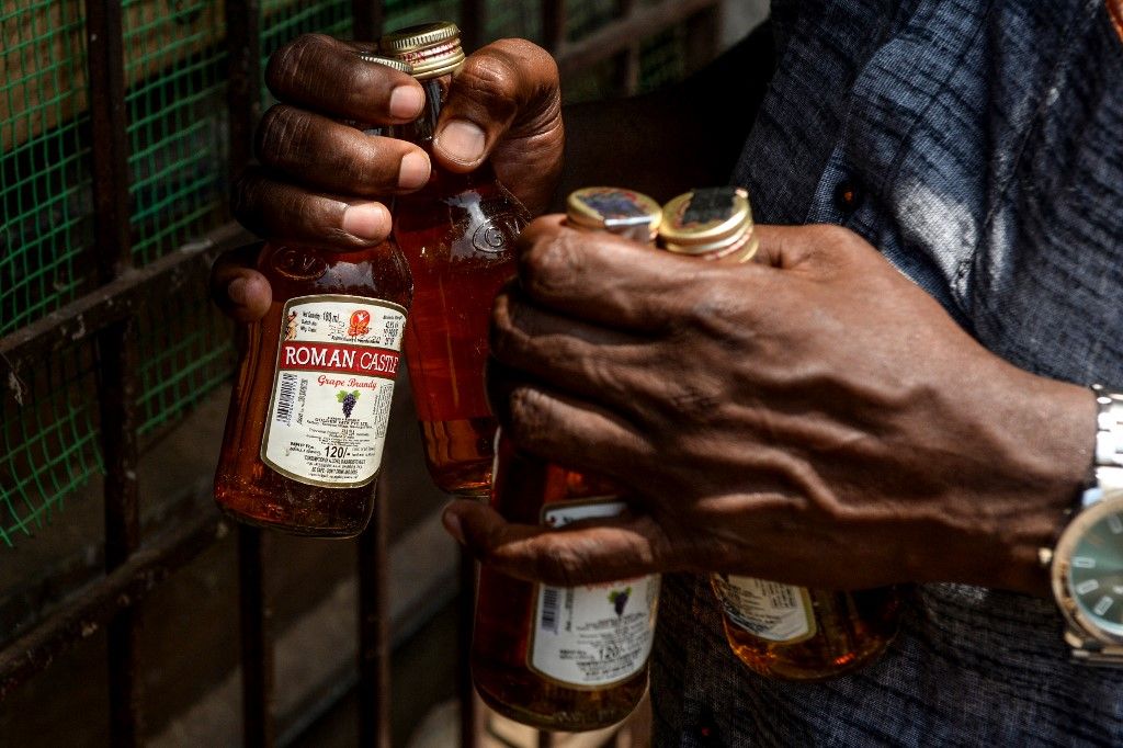 A man carries bottles of alcohol bought from a liquor shop after the government eased a nationwide lockdown imposed as a preventive measure against the COVID-19 coronavirus, on the outskirts of Chennai on May 7, 2020. (Photo by Arun SANKAR / AFP), alkoholmérgezés, metil-alkohol