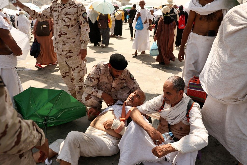 (FILES) A man effected by the scorching heat is helped by a member of the Saudi security forces as Muslim pilgrims arrive to perform the symbolic 'stoning of the devil' ritual as part of the hajj pilgrimage in Mina, near Saudi Arabia's holy city of Mecca, on June 16, 2024. Friends and family searched for missing hajj pilgrims on June 19, 2024, as the death toll at the annual rituals, which were carried out in scorching heat, surged past 900. About 1.8 million people from all over the world, many old and infirm, took part in the days-long, mostly outdoor pilgrimage, held this year during the oven-like Saudi summer. (Photo by Fadel Senna / AFP) mekkai zarándoklat
