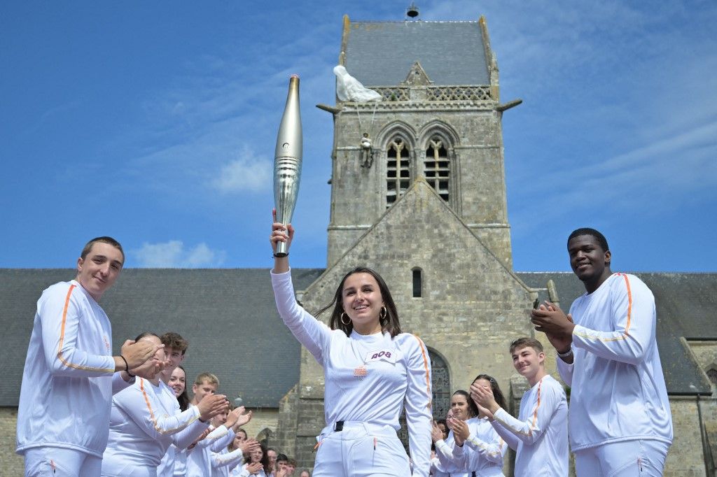 Torch bearer Fanny Rivallant holds the Olympic flame as part of the Olympic Relay ahead of the Paris 2024 Olympic and Paralympic Games, in Sainte-Mere-Eglise, Normandy, on May 31, 2024. (Photo by Lou Benoist / AFP)