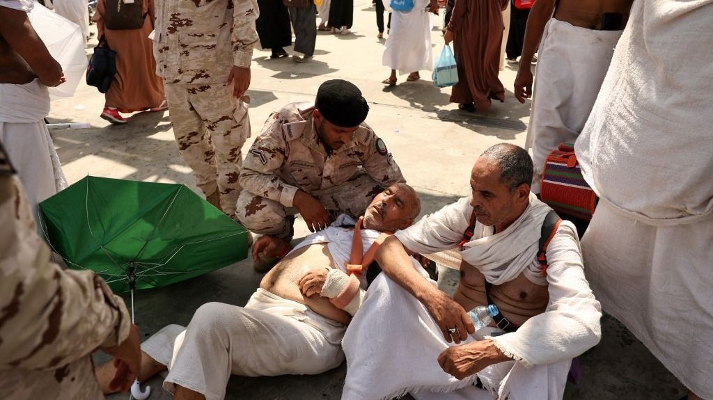 (FILES) A man effected by the scorching heat is helped by a member of the Saudi security forces as Muslim pilgrims arrive to perform the symbolic 'stoning of the devil' ritual as part of the hajj pilgrimage in Mina, near Saudi Arabia's holy city of Mecca, on June 16, 2024. Friends and family searched for missing hajj pilgrims on June 19, 2024, as the death toll at the annual rituals, which were carried out in scorching heat, surged past 900. About 1.8 million people from all over the world, many old and infirm, took part in the days-long, mostly outdoor pilgrimage, held this year during the oven-like Saudi summer. (Photo by Fadel Senna / AFP) hőhullám