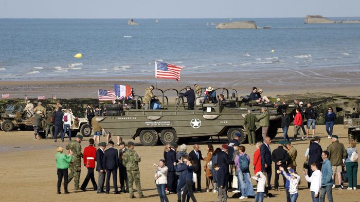 A bámészkodók a DUKW kétéltű teherautóival gyülekeznek az északnyugat-franciaországi Arromanches-les-Bains tengerpartján
