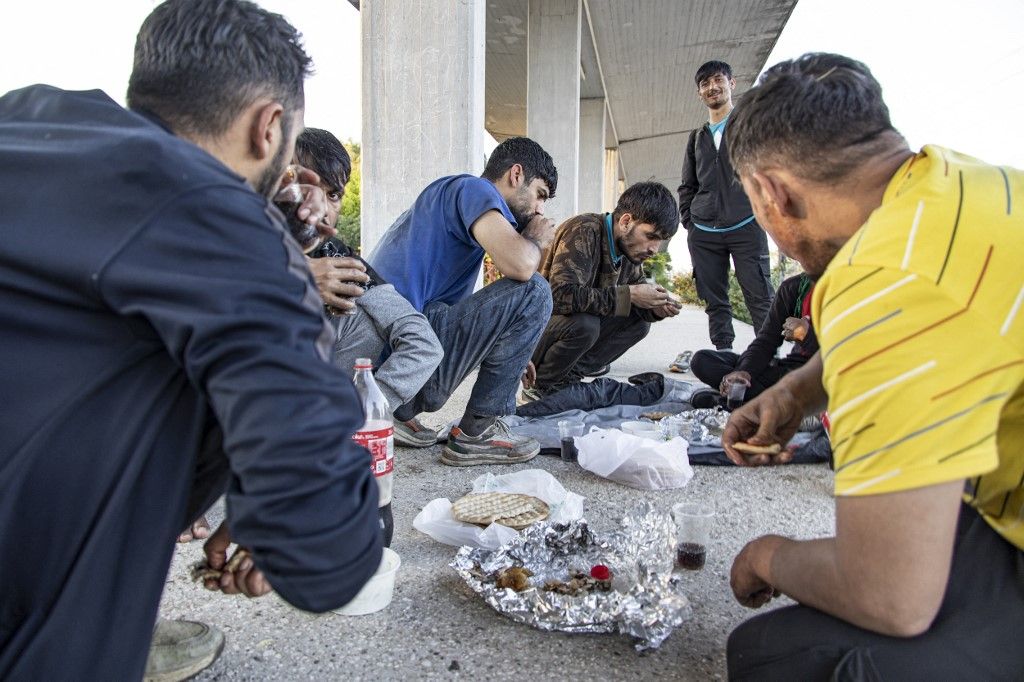 Asylum seekers as seen at Idomeni railway station, a few meters before the borderline between Greece and Northern Macedonia as seen resting and eating. They wait and form groups to cross the borders in the mountains and reach other European countries like Germany, France, Sweden etc via the Balkan route.  Refugees and migrants arrive at the train station from Turkey or Thessaloniki after a long multi-day journey on foot following marked routes in social media or the rails and highway but others via smugglers paying sometimes 2500 euro to smugglers to move them from Turkey here. Some of them complained for pushbacks from the N. Macedonian police after treating them violently and beating them. The station and the fenced part of the borders were guarded by Greek police and European Frontex forces. Most of the group were from Afghanistan, some from Syria, Iraq, Palestine, Pakistan, and Morocco. The flows of people arriving from Turkey are increasing every day as the refugee and migrant crisis is still ongoing. Eidomeni, Greece on October 2022  (Photo by Nicolas Economou/NurPhoto) (Photo by Nicolas Economou / NurPhoto / NurPhoto via AFP)