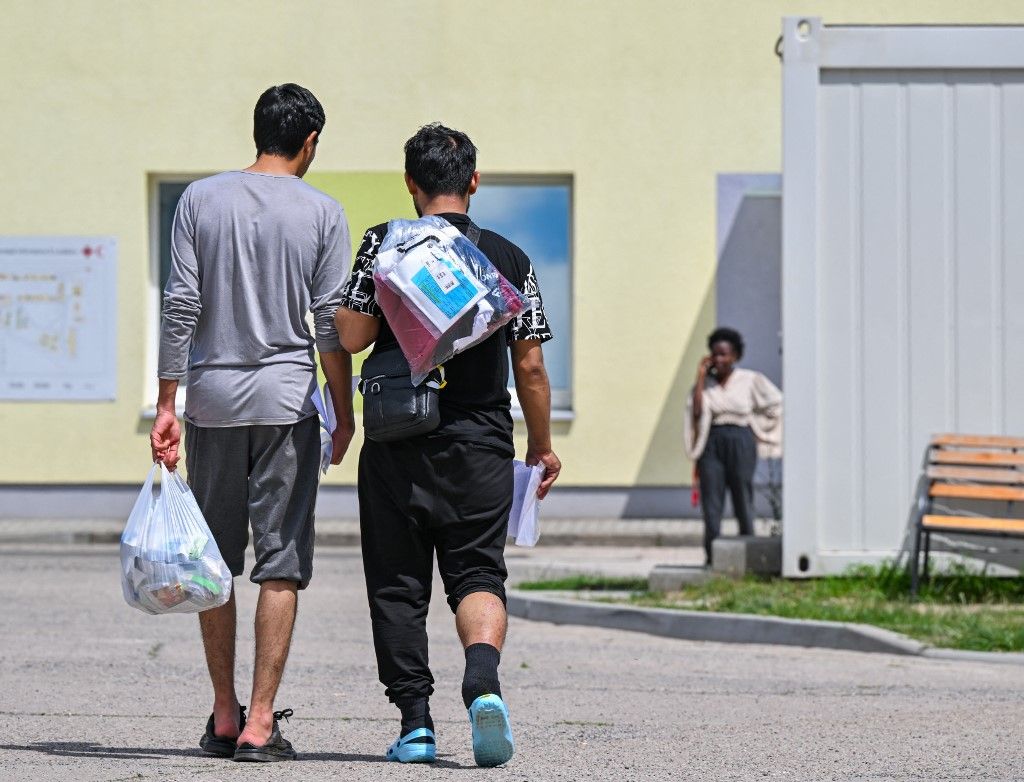 18 June 2024, Brandenburg, Eisenhüttenstadt: Two migrants walk across the grounds of the Central Reception Center for Asylum Seekers (ZABH) in the state of Brandenburg. On June 20, the Conference of Minister Presidents will discuss the question of whether asylum procedures for asylum seekers can be transferred to a cooperating state outside the EU while respecting international and human rights law. Photo: Patrick Pleul/dpa (Photo by PATRICK PLEUL / DPA / dpa Picture-Alliance via AFP)