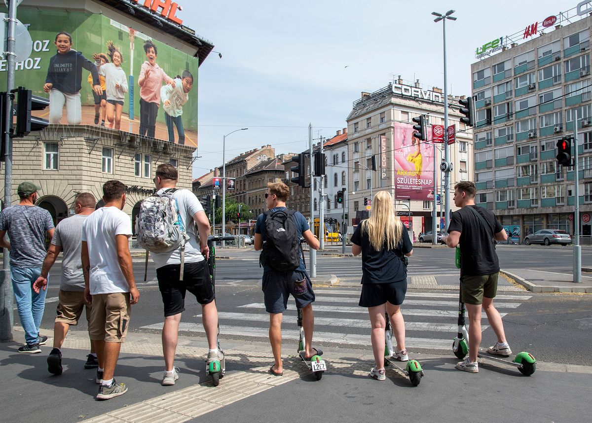 Budapest, 2022. augusztus 13.Fiatalok közösségi használatú e-rollerekkel várakoznak áthaladásra a gyalogátkelőhelyen, az Üllői út és a Ferenc körút találkozásánál. A fővárosi közgyűlés korábban mikromobilitási pontok létrehozását és a szolgáltatás működtetésének alapelveit határozta meg. Először a belső kerületekben hozták létre azokat a pontokat, ahol felvenni és leadni lehet az eszközöket, hogy csökkentsék a mikromobilitási eszközök nem kijelölt helyeken történő parkoltatását.MTVA/Bizományosi: Róka László ***************************Kedves Felhasználó!Ez a fotó nem a Duna Médiaszolgáltató Zrt./MTI által készített és kiadott fényképfelvétel, így harmadik személy által támasztott bárminemű – különösen szerzői jogi, szomszédos jogi és személyiségi jogi – igényért a fotó szerzője/jogutódja közvetlenül maga áll helyt, az MTVA felelőssége e körben kizárt.