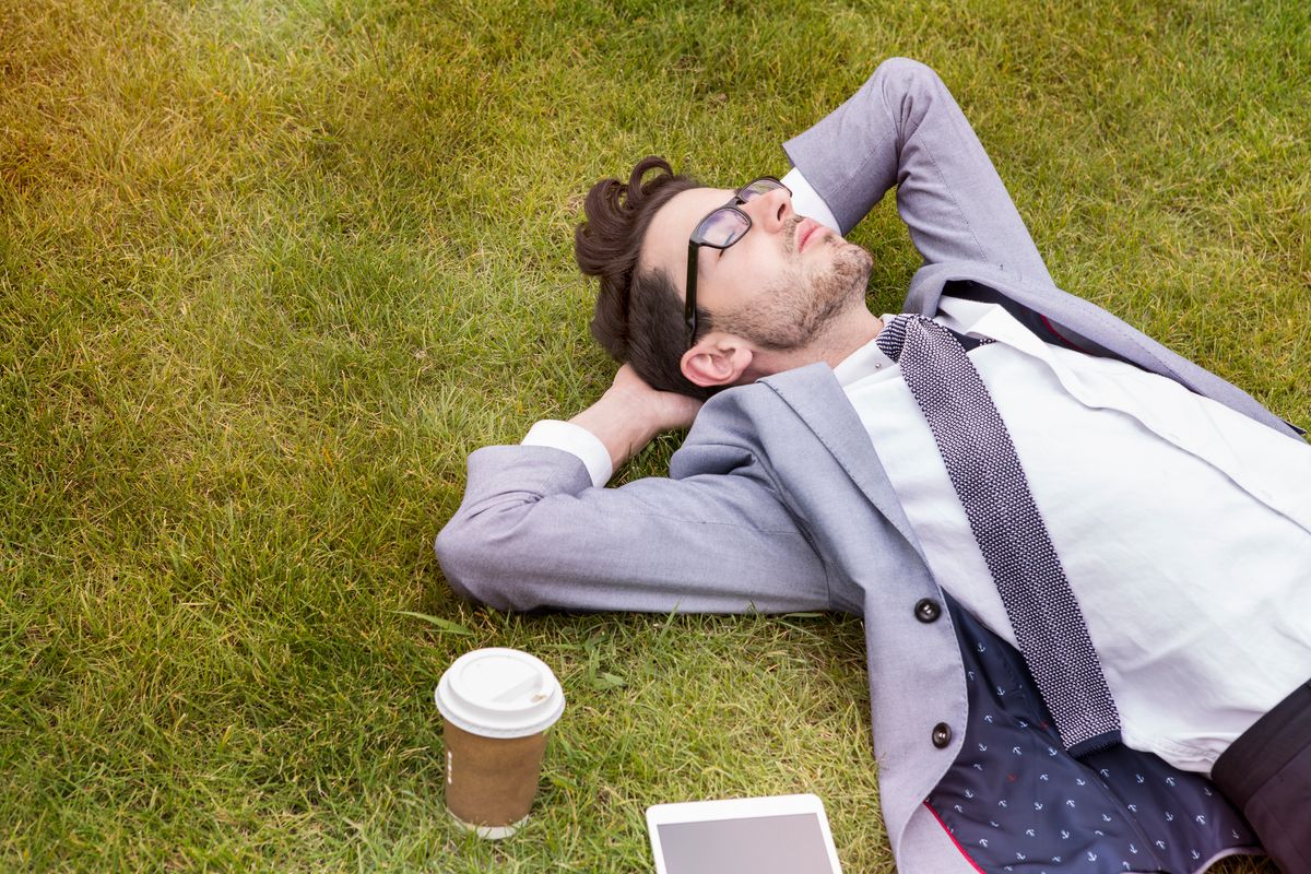 business person having break, laying in park.