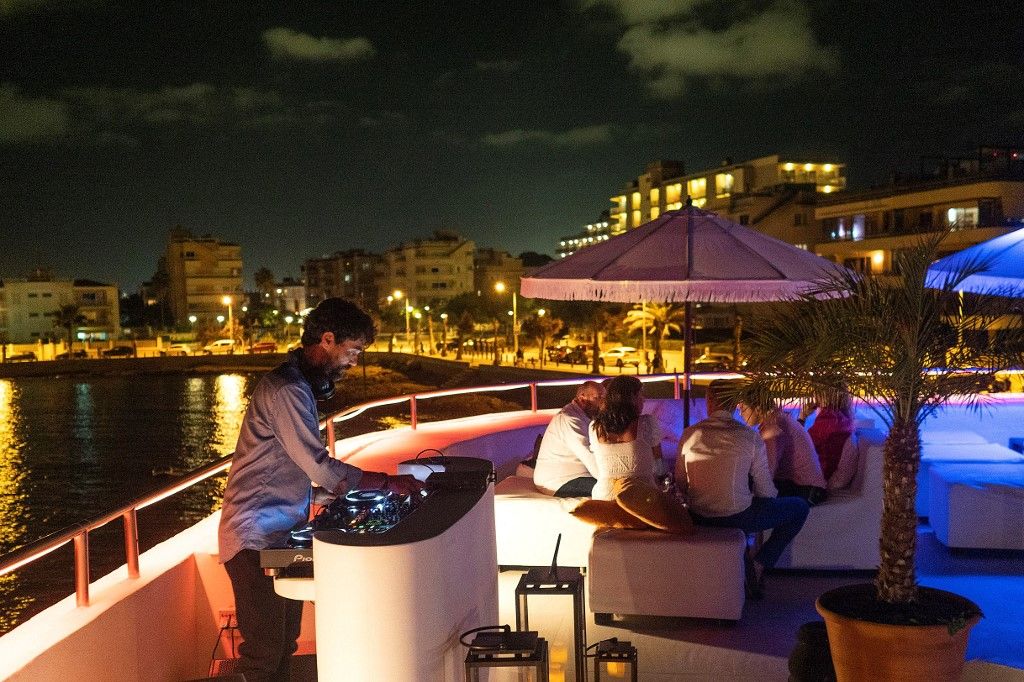 A DJ performs at a private party at a beach club at Can Pastilla in Palma de Mallorca on August 5, 2021. Spain's economy contracted sharply by 10.8 percent in 2020, one of the worst results in the eurozone, with its key tourism sector battered by the pandemic travel restrictions. But it returned to growth in the second quarter of 2021 and the government predicts it will expand by 6.5 percent this year. (Photo by JAIME REINA / AFP)