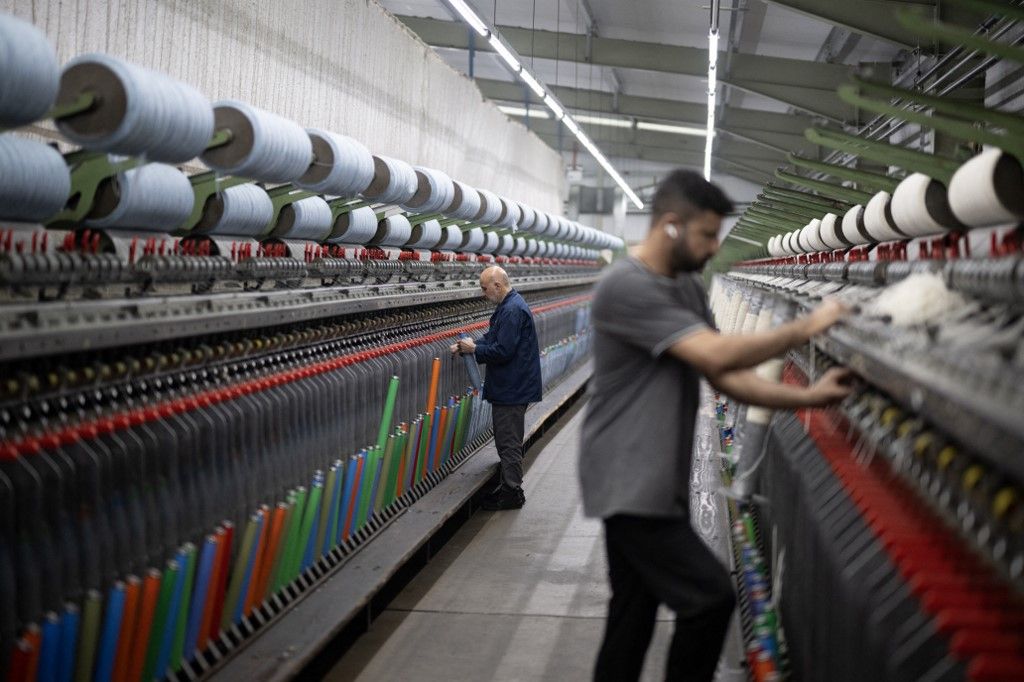 An employee at Mallalieus' mill works on a spinning machine, in Delph, near Oldham, northern England on January 17, 2024. Founded in 1863, Mallalieus operate one of the last remaining vertical woollen mill in England, with dyeing, blending, carding, spinning, weaving and finishing processes all taking place in the village. The mill produces fabrics for both the clothing and furnishing industries. The company was founded by brothers David and Henry Mallalieu who were descended from French Protestant Huguenots. Renowned for their expertise in weaving, their ancestors had fled to England in 1572 to escape religious persecution. Since medieval times the area around Delph has been a centre for woollen weaving, owing to the local availability of sheep wool and soft water. (Photo by Oli SCARFF / AFP)