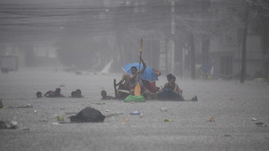 Rescuers paddle their boats along a flooded street in Manila on July 24, 2024 amid heavy rains brought by Typhoon Gaemi. Relentless rain drenched the northern Philippines on July 24, triggering flooding in Manila and landslides in mountainous regions as Typhoon Gaemi intensified the seasonal monsoon. (Photo by Ted ALJIBE / AFP)