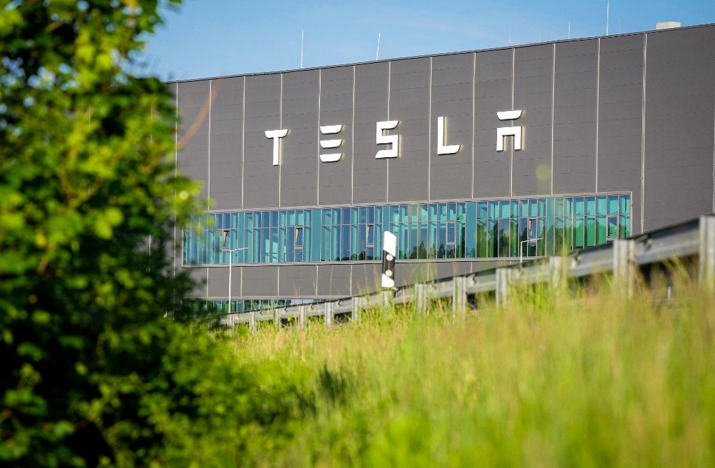 17 May 2024, Brandenburg, Grünheide: The lettering "Tesla" is on the façade of a Tesla Gigafactory building. The grass-covered embankment of the L38 road can be seen in the foreground. On Thursday evening, municipal representatives from Grünheide approved a development plan that clears the way for the expansion of the Tesla factory. The car manufacturer wants to expand its site to include a freight yard and logistics areas. Photo: Soeren Stache/dpa (Photo by SOEREN STACHE / DPA / dpa Picture-Alliance via AFP)