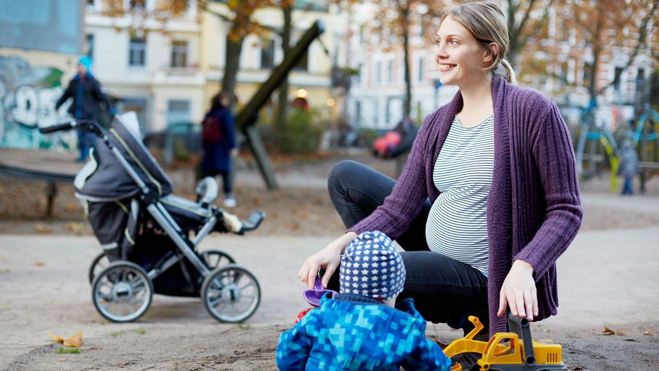 Pregnant mom playing with toddler on playground