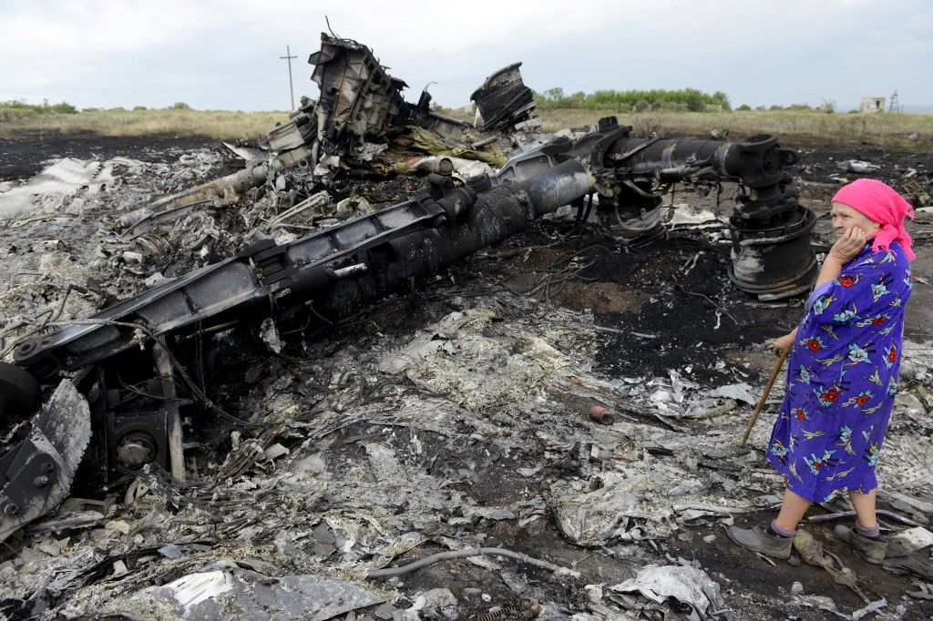 (FILES) A local resident stands among the wreckage at the site of the crash of Malaysia Airlines MH-17 aircraft carrying 298 people from Amsterdam to Kuala Lumpur at Grabove, in rebel-held east Ukraine on July 19, 2014. The families of the victims of the downing of flight MH17 in war-torn eastern Ukraine are this week commemorating ten years since the tragedy, with dwindling hopes of seeing those responsible behind bars. (Photo by Alexander KHUDOTEPLY / AFP)