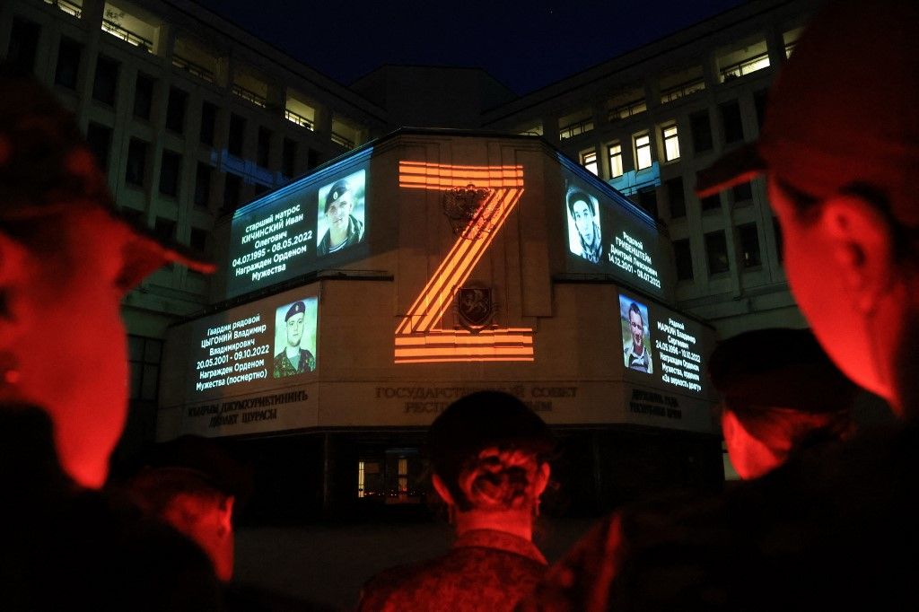 Portraits of Russian service members killed in the ongoing Russian-Ukrainian conflict and the "Z" letter are seen projected onto the State Council building during a memorial ceremony in Simferopol, Crimea, on April 9, 2024. (Photo by STRINGER / AFP)