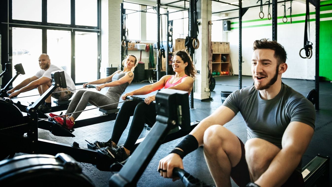 A fitness group exercising together with rowing machines at the gym together.