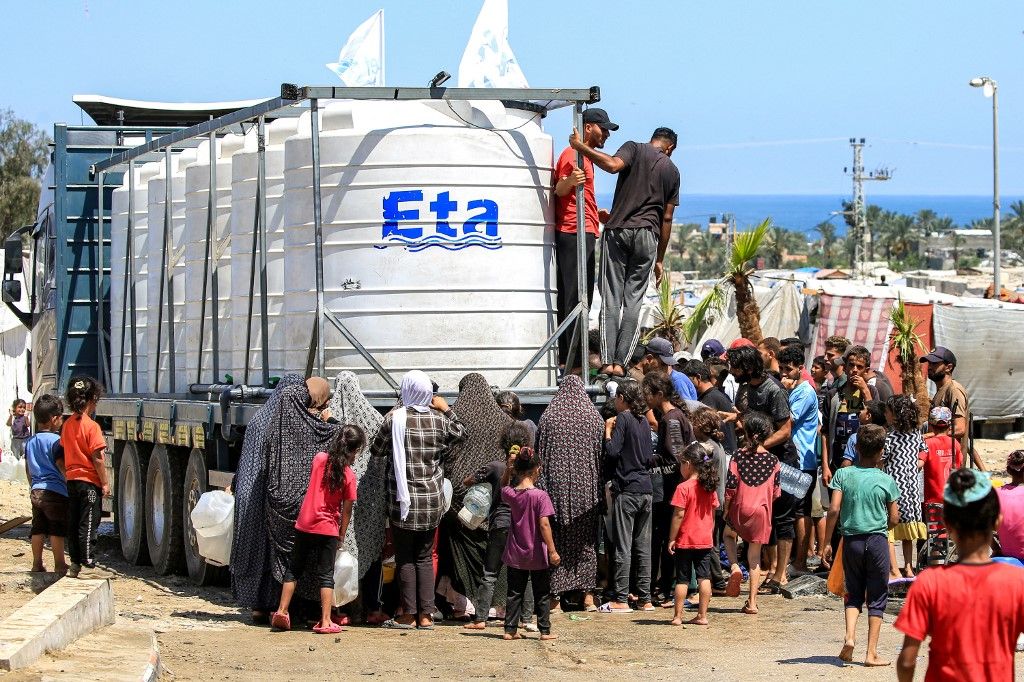People gather to fill up their water containers from a truck loaded with water cisterns in Rafah in the southern Gaza Strip on June 25, 2024 amid the ongoing conflict in the Palestinian territory between Israel and Hamas. (Photo by Eyad BABA / AFP)