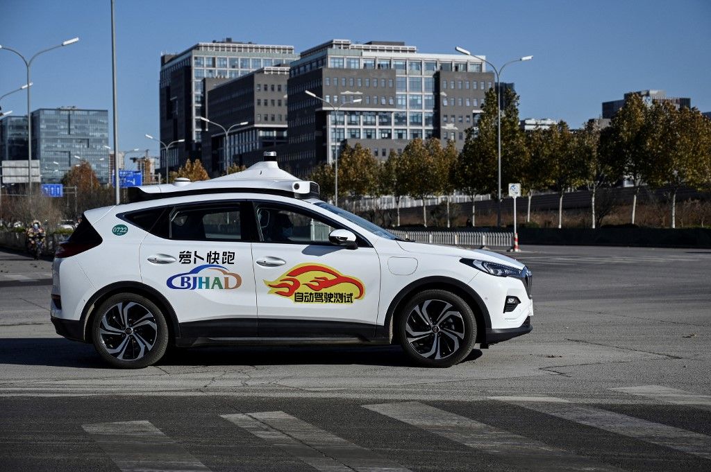 An Apollo Go autonomous taxi is seen on a street in Yizhuang, a town of Daxing District, in the southeast suburbs of Beijing on November 26, 2021. Beijing this week approved its first autonomous taxis for commercial use, bringing dozens of the so-called "robotaxis" to the streets of the Chinese capital. An employee of the taxi firm also sits in the front of the car in case any sudden intervention is needed, but the vehicle drives itself. (Photo by Jade GAO / AFP) / TO GO WITH AFP STORY CHINA-ECONOMY-TRANSPORT-TECHNOLOGY