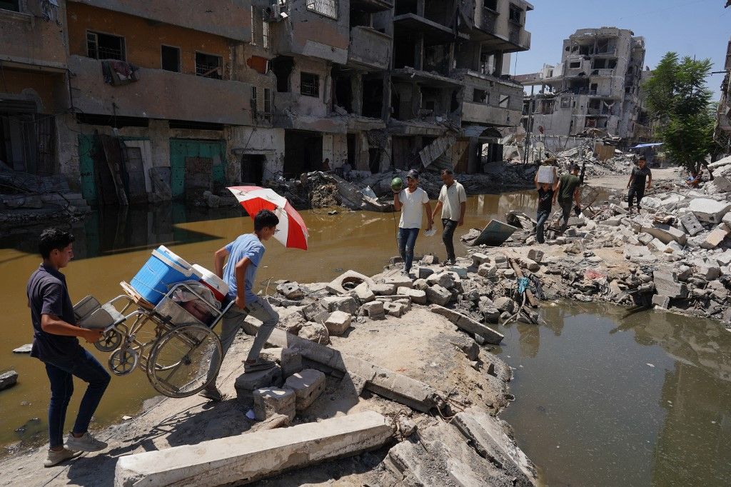 Palestinians walk on the rubble of buildings destroyed in previous Israeli bombardment, between two pools of stagnant water, in Khan Yunis in the southern Gaza Strip on July 19, 2024, as the conflict between Israel and the Palestinian militant group Hamas continues. The Israeli health ministry said poliovirus type 2 was detected in Gaza sewage samples tested in an Israeli laboratory, adding that the World Health Organization had made similar findings. The war has destroyed much of Gaza's housing and other infrastructure, leaving almost all of the population displaced and short of food and drinking water.



The Israeli health ministry said poliovirus type 2 was detected in Gaza sewage samples tested in an Israeli laboratory, adding that the World Health Organization had made similar findings. (Photo by Bashar TALEB / AFP)