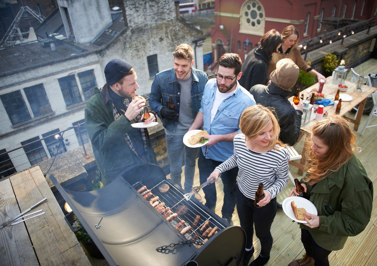 Friends in roof garden sharing barbecued food.