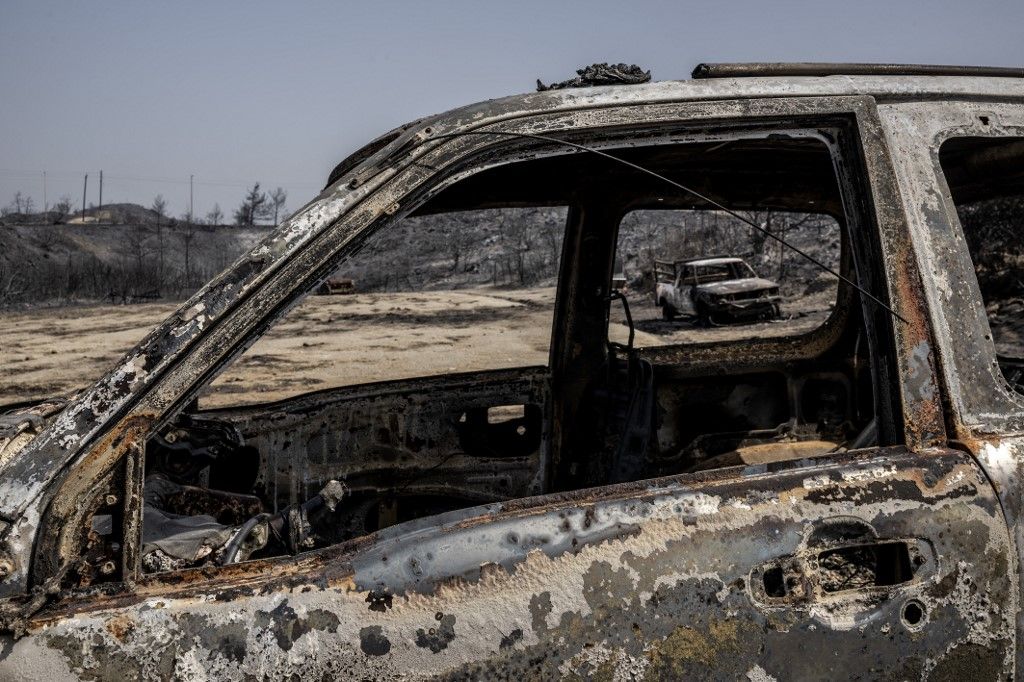 The remains of burnt out vehicles caught in the wild fires litter the grounds close to the village of Gennadi, in the southern part of the Greek island of Rhodes, on July 27, 2023. Wildfires have been raging in Greece amid scorching temperatures, forcing mass evacuations in several tourist spots including on the islands of Rhodes and Corfu. (Photo by Angelos Tzortzinis / AFP)