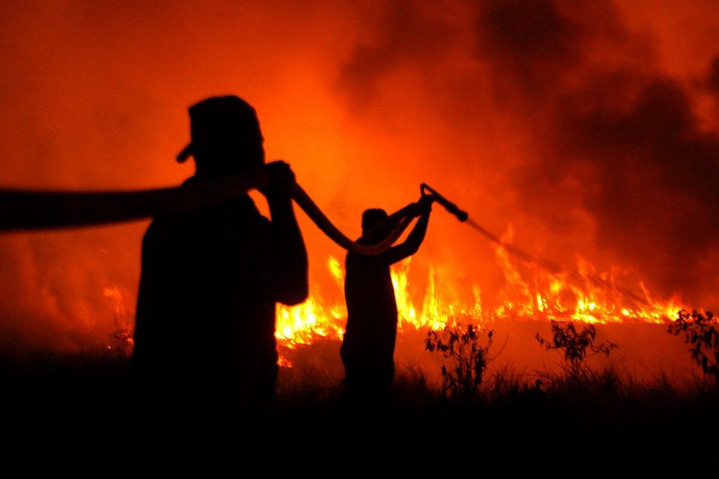 OGAN ILIR, INDONESIA - SEPTEMBER 12: Indonesian police officers try to extinguish wildfire in Ogan Ilir, South Sumatera, Indonesia on September 12, 2023. Southeast Asia could see the return of transboundary haze later this year, as Indonesia battles an increased number of wildfires amid a prolonged dry season. Haze in Southeast Asia due to forest fires in Indonesia has been a perennial issue over the past decades. Muhammad A.F / Anadolu Agency (Photo by Muhammad A.F / ANADOLU AGENCY / Anadolu via AFP)