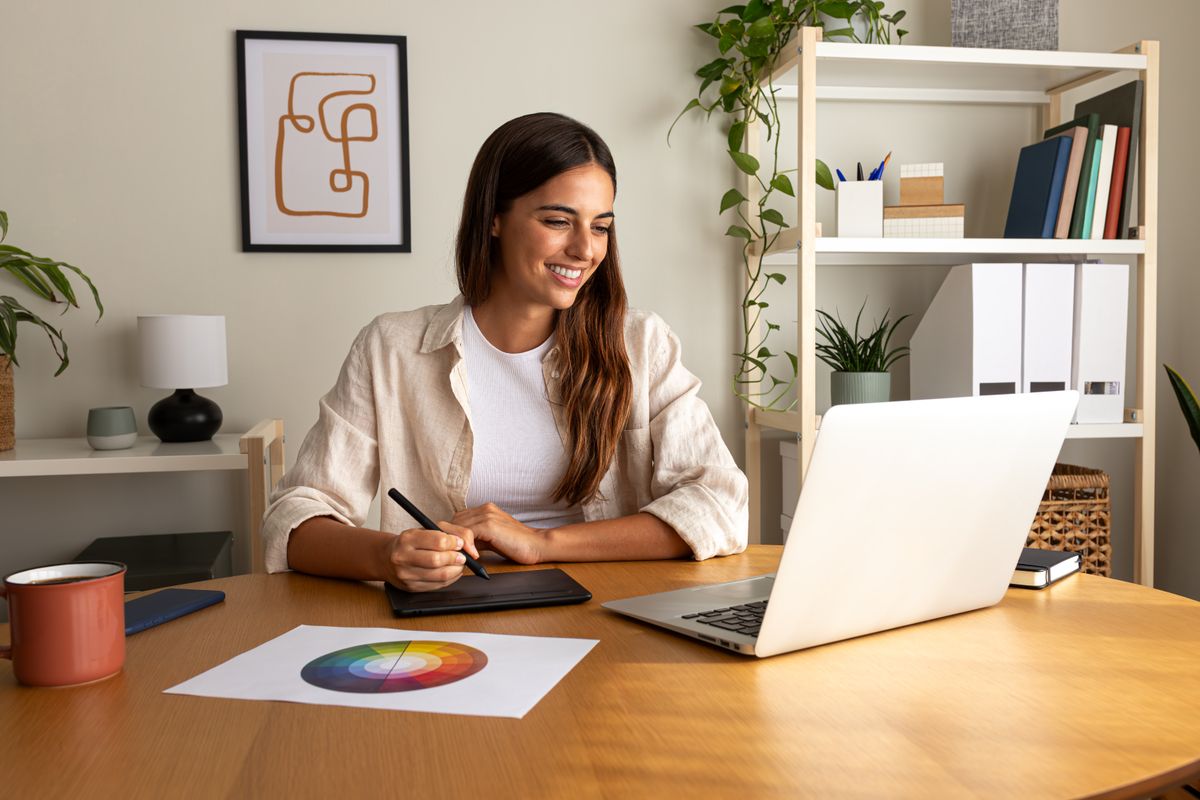 Female graphic designer working at home using laptop and graphic tablet. home office