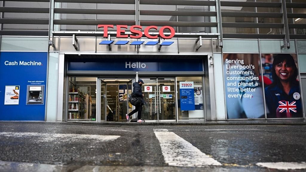 A pedestrian walks past a Tesco supermarket, in Liverpool, northern England, on April 10, 2024. Supermarket group Tesco, Britain's biggest retailer, reported on April 10, 2024 that its annual net profit surged 61 percent as easing UK inflation helped cost-conscious shoppers buy more products. (Photo by Paul ELLIS / AFP)