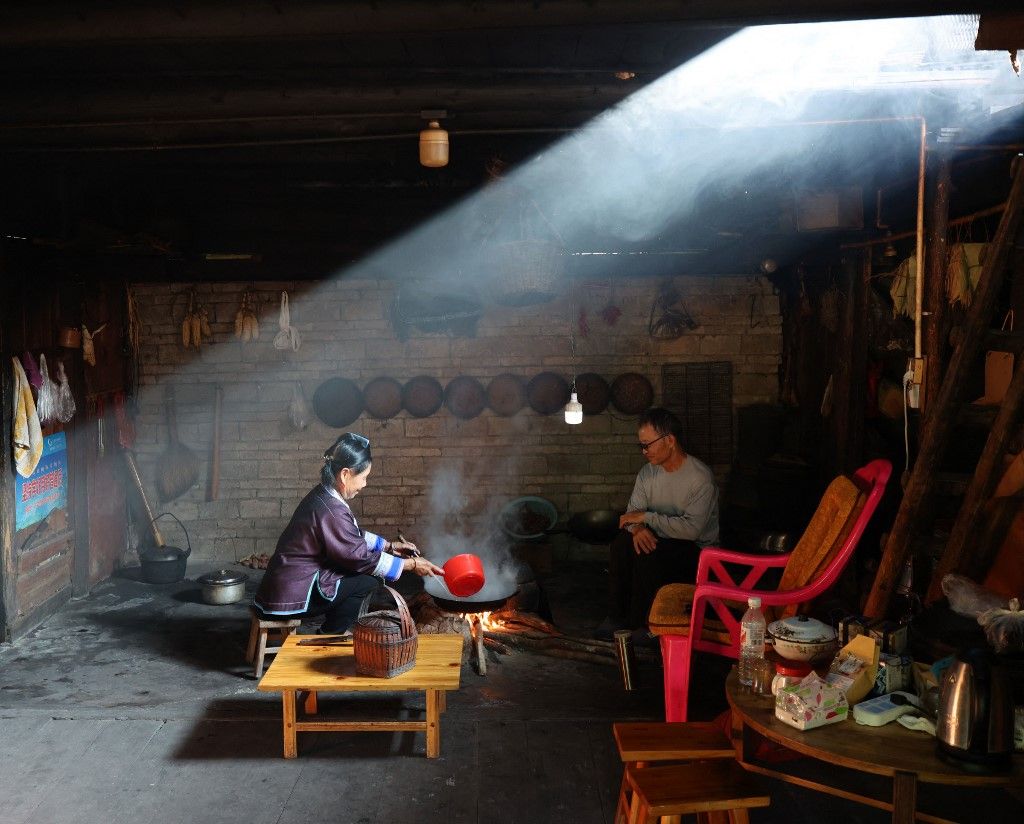 (240912) -- LIUZHOU, Sept. 12, 2024 (Xinhua) -- Liang Anhe (R) and his wife Liang Yingmi prepare oil tea at home at Wuying Village on the border between south China's Guangxi Zhuang Autonomous Region and southwest China's Guizhou Province, Sept. 4, 2024.
  Wuying Village is a Miao ethnic-minority hamlet that nestles snugly in the towering mountains stretching across the border between Guangxi and Guizhou. The impassable mountains and rugged landscape used to render locals extremely poor, but villagers Liang Anhe, 74, and his son Liang Xiuqian, 45, have witnessed great changes and development in the village over the past decade.
   The senior Liang had raised his children with scanty salaries from labors at his 0.13-hectare filed and serving as a substitute teacher at a primary school. The junior Liang, once a migrant worker, returned to the village over ten years ago and kept searching for opportunities of fortune in various walks of life. He became a leader of the fruit planting cooperative incorporated at the village in 2017.
   Thanks to supporting efforts from pertinent authorities, Wuying has undergone significant changes over recent years, with the establishment of new classroom buildings, cultural corridors, public squares as well as a women's night school and an education fund. 
   As a teacher at the women's night school, the senior Liang guides students there in learning, tree planting, and event hosting. The junior Liang, for his part, spearheads with the local Lusheng (a traditional reed-pipe wind instrument) team as it wins honor for the village from various art competitions. (Xinhua/Jin Haoyuan) (Photo by Jin Haoyuan / XINHUA / Xinhua via AFP)