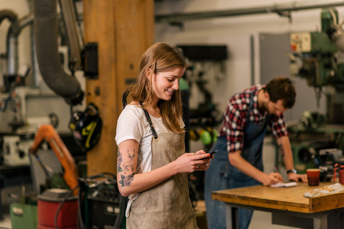 young craftswoman smiling and texting, kkv