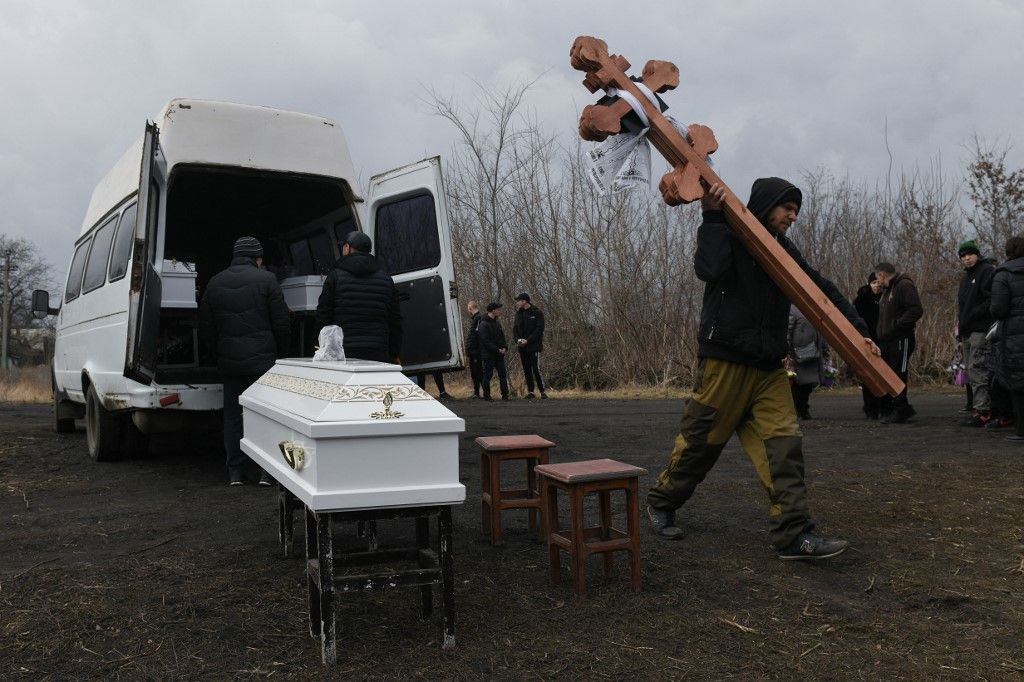 EDITORS NOTE: Graphic content / A man carries wooden crosses during a funeral ceremony of three children, killed in what local Moscow-installed officials say was a Ukrainian attack, in Donetsk, Russian-controlled Ukraine, on March 17, 2024, amid ongoing Russian-Ukrainian conflict. (Photo by STRINGER / AFP)