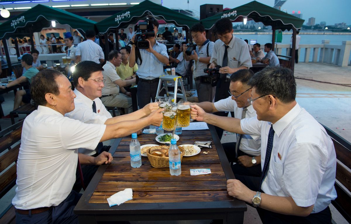 This photo taken on August 12, 2016 shows Choe Yong Nam (L), director of the General Bureau of Public Service who doubles as chairman of the preparatory committee for the festival, saying "cheers" with other officials after the opening ceremony of the Pyongyang Taedonggang Beer Festival on the banks of the Taedong river in Pyongyang. (Photo by Kim Won-Jin / AFP)