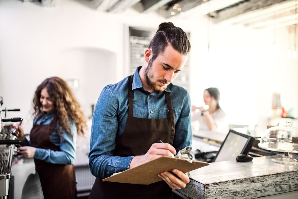 Two,Young,Baristas,Working,In,Coffee,Shop,,Standing,By,Counter.