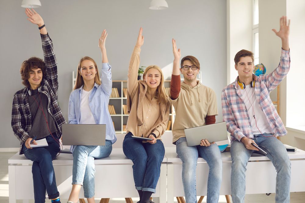 Group,Of,Happy,Smiling,Active,Students,Raising,Hands,Sitting,On