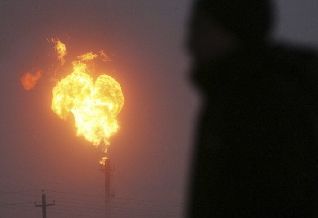 karbonkibocsátás A man watches natural gas flaring at a Gazprom facility in the town Novy Urengoi , 17 December 2007, during -40 degrees celcius weather conditions. Just below the arctic circle at 66 degress north latitude, Novy Urengoi is home to various natural gas facilities of Russian gas giant Gazprom.     AFP PHOTO / NATALIA KOLESNIKOVA (Photo by NATALIA KOLESNIKOVA / AFP)