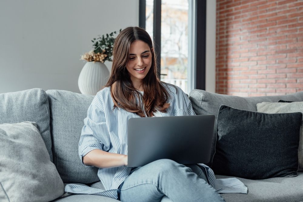 Concentrated,Millennial,Girl,Sit,On,Couch,Working,On,Laptop,Browsing
internet