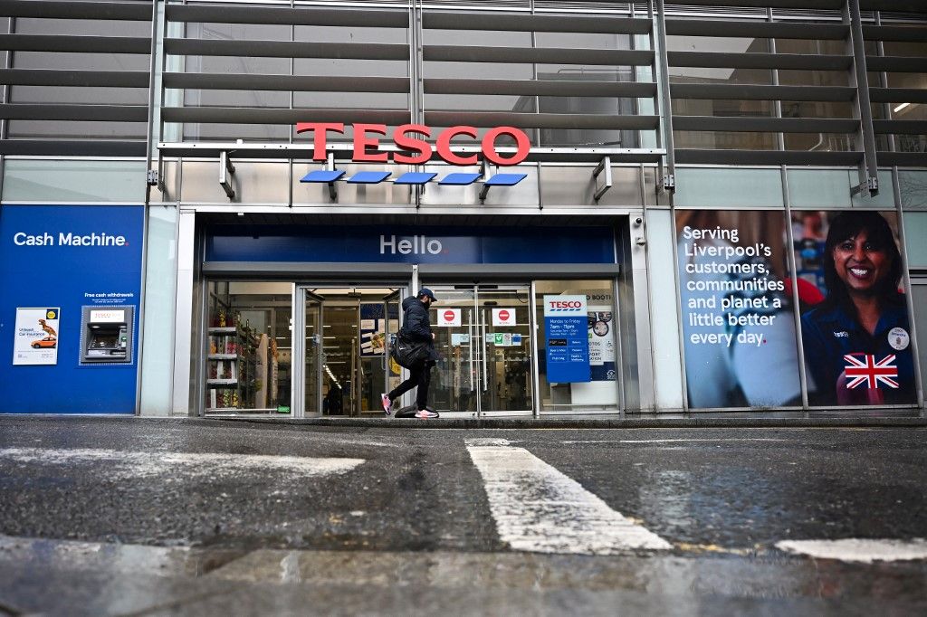 A pedestrian walks past a Tesco supermarket, in Liverpool, northern England, on April 10, 2024. Supermarket group Tesco, Britain's biggest retailer, reported on April 10, 2024 that its annual net profit surged 61 percent as easing UK inflation helped cost-conscious shoppers buy more products. (Photo by Paul ELLIS / AFP)