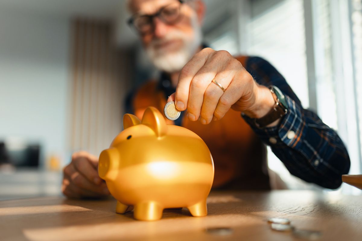 Senior man putting coins, money into a piggy bank. Saving Money after retirement, preparing for retirement. Financial education and financial literacy for seniors.
pénzügyi egészség, pénzügyi tudatosság