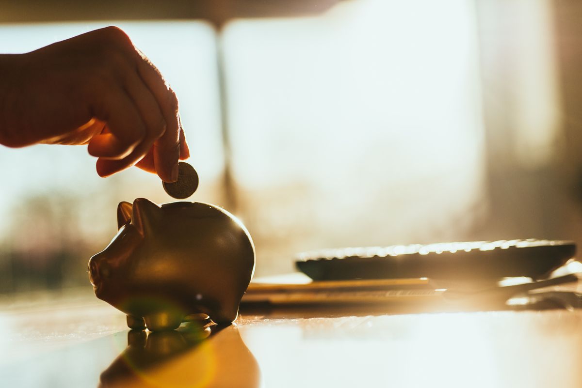 Putting a coin in a gold colored piggy bank at home.
rekordon a háztartások megtakarításai, nő a pénzügyi vagyon