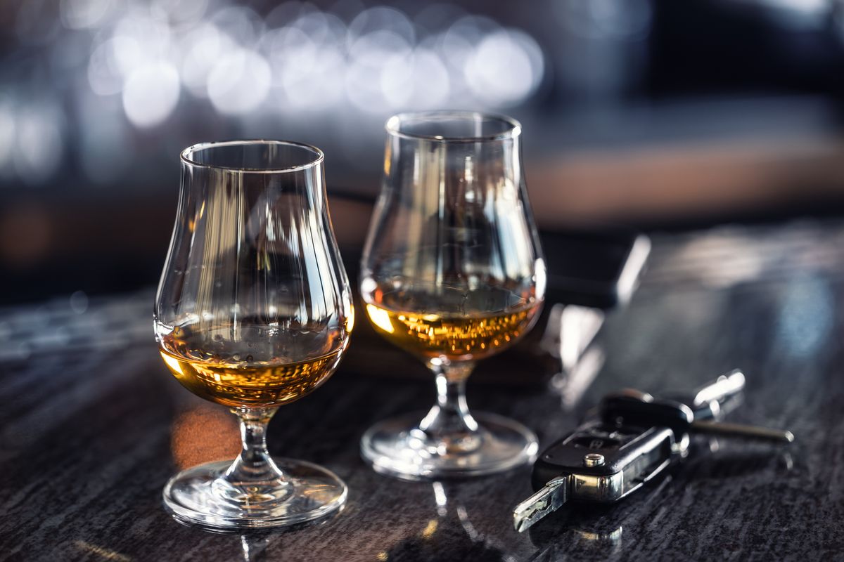 Iszik, vagy vezet? Az Európai Unhió és Kína között vámháború kezdődött, keleten a francia brandy drágul meg először, nyugaton a kínai elektromos autó A glass of rum or cognac on the bar counter together with the car keys. Concept of driving a car under the influence of alcohol or drugs.