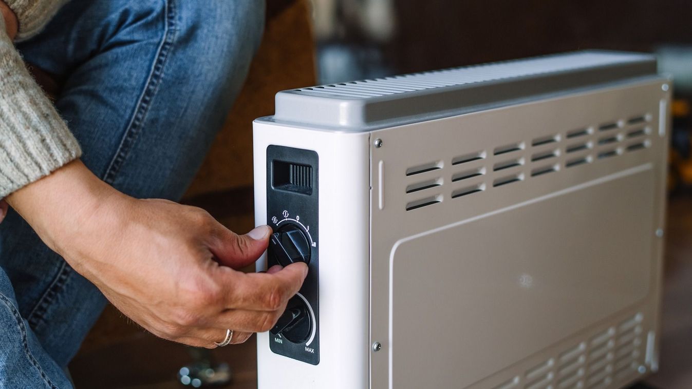 Man turning on a domestic portable radiator/heater in cold winter