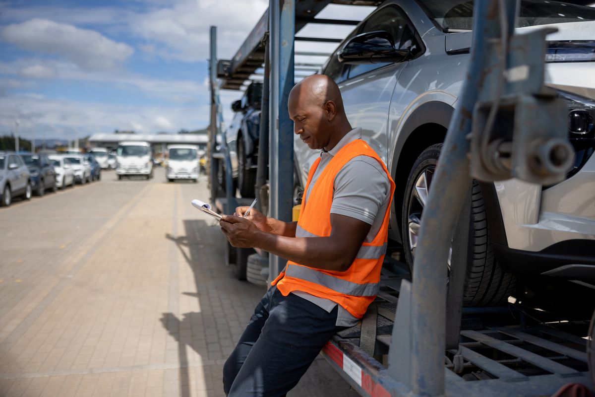 Man supervising the shipment of vehicles on a car transporter
autó