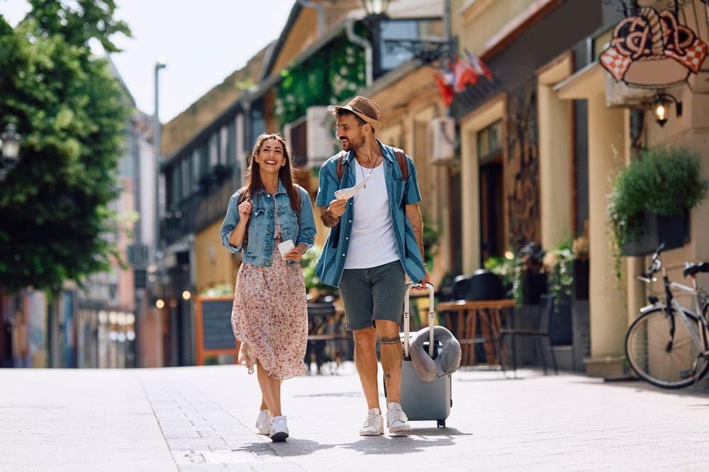 Happy,Couple,Of,Tourists,Walking,In,The,City,While,Traveling