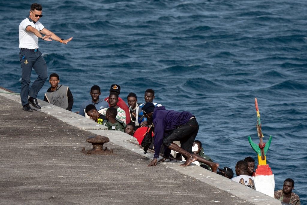 A captain of Spanish Salvamento Maritimo (Sea Search and Rescue agency) gestures as a person gets off a boat from Senegal, with 85 migrant people on board, after arriving at La Restinga port, on the Canary island of El Hierro, on August 19, 2024. Spain's left-wing government is grappling with a major upsurge in migrant arrivals, notably in the Canary Islands, which has left the Atlantic archipelago feeling increasingly abandoned by Madrid and Brussels. Not a day passes without Spain's coastguard rescuing at least one troubled boat carrying dozens of African migrants towards the islands which are located off the northwestern coast of Africa. The rising numbers have prompted Prime Minister Pedro Sanchez's latest diplomatic foray into West Africa where on August 27 he begins a three-day visit to the main countries concerned: Mauritania, The Gambia and Senegal. (Photo by Jose Antonio SEMPERE / AFP)