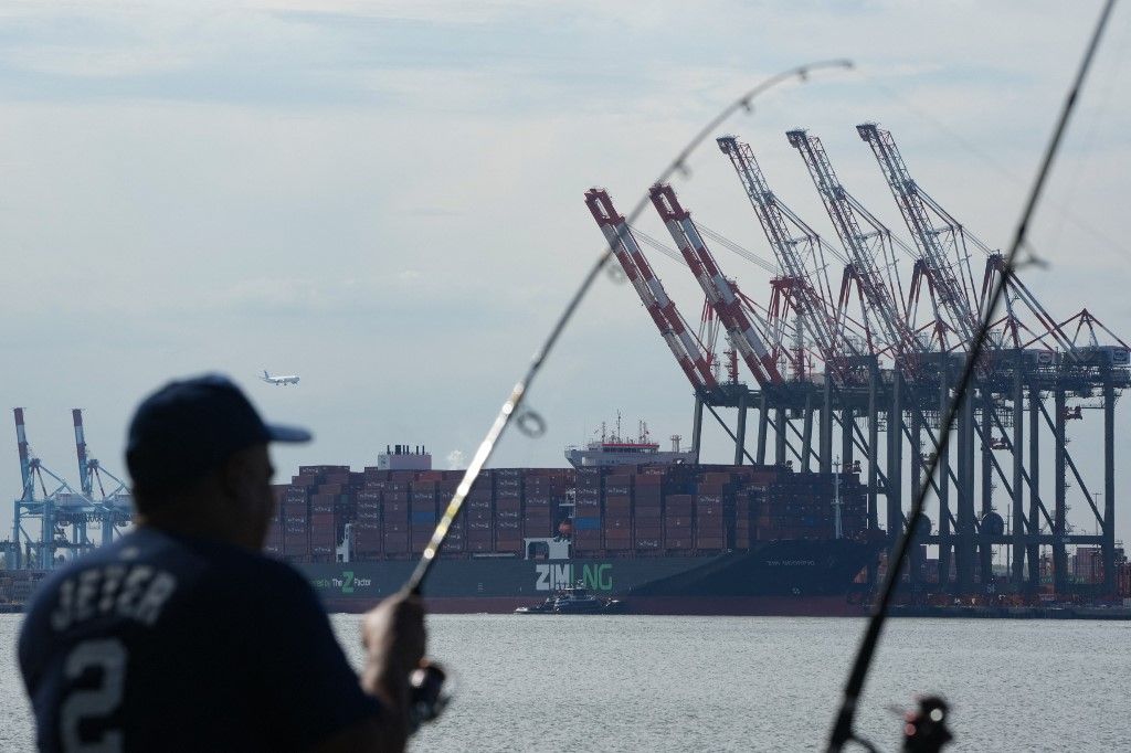 A man fishes from a pier in Bayonne near Port Newark Shipping Terminal as East Coast Ports may shut down due to a potential dockworker strike in New Jersey on September 30, 2024. Tens of thousands of US dockworkers plan to strike this week if there is no breakthrough on contract talks, just a month be