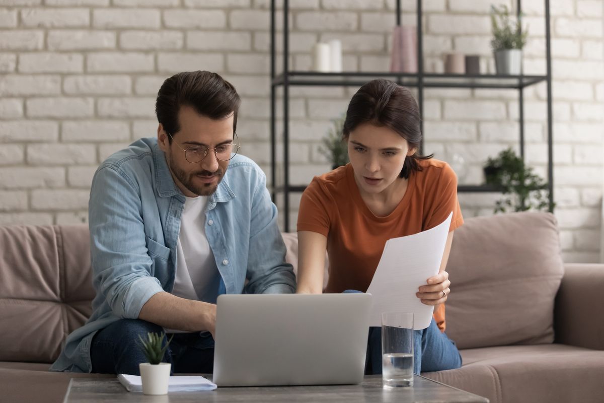 Focused young married couple looking at computer screen, planning budget.