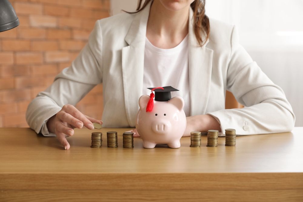 Woman,In,Business,Suit,Sitting,At,Table,With,Piggy,Bank