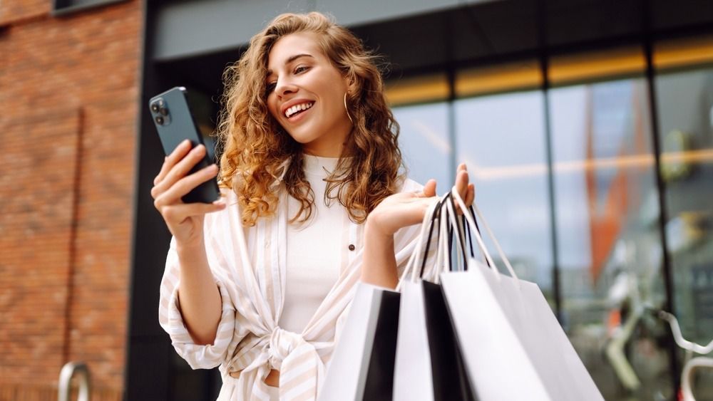 Young,Woman,Use,Of,Mobile,Phone,And,Hold,With,Shopping vásárlás